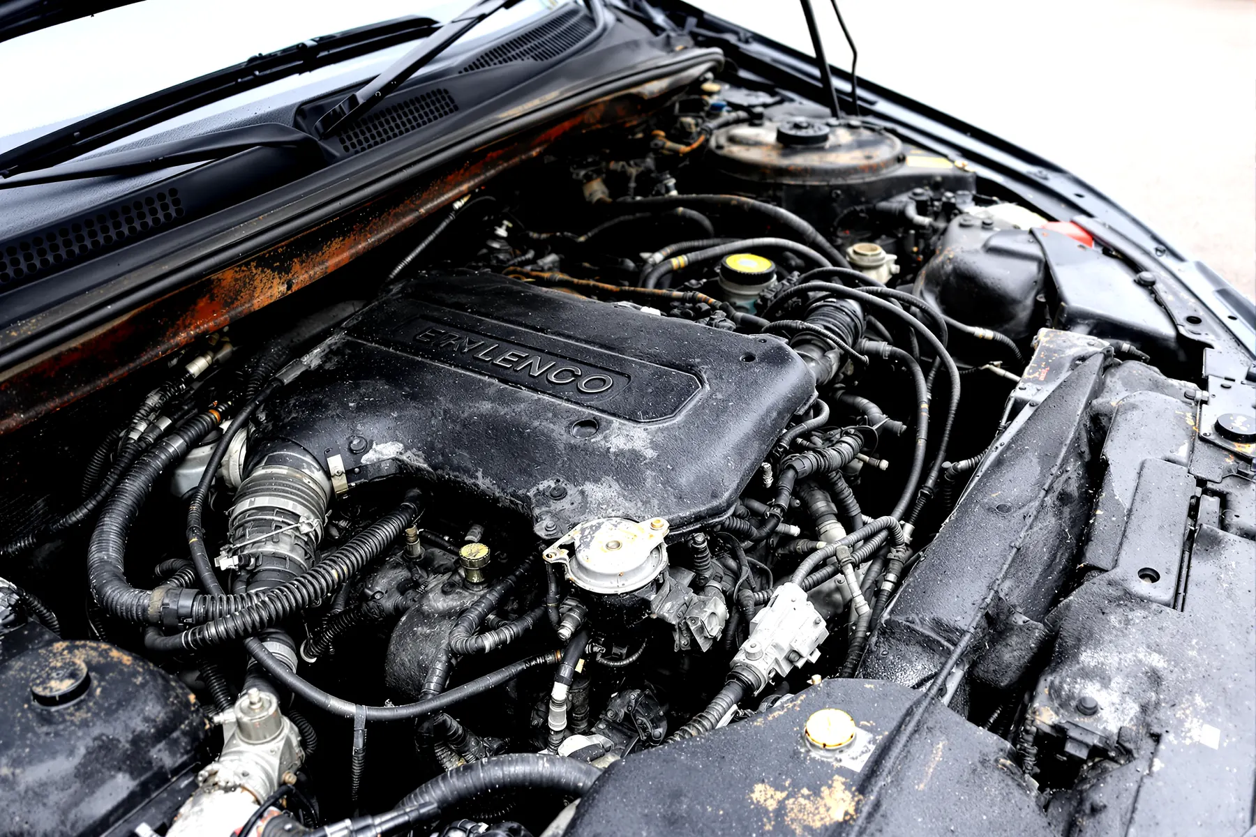 Illustration: close-up of a soot-blackened car engine bay after an engine fire.