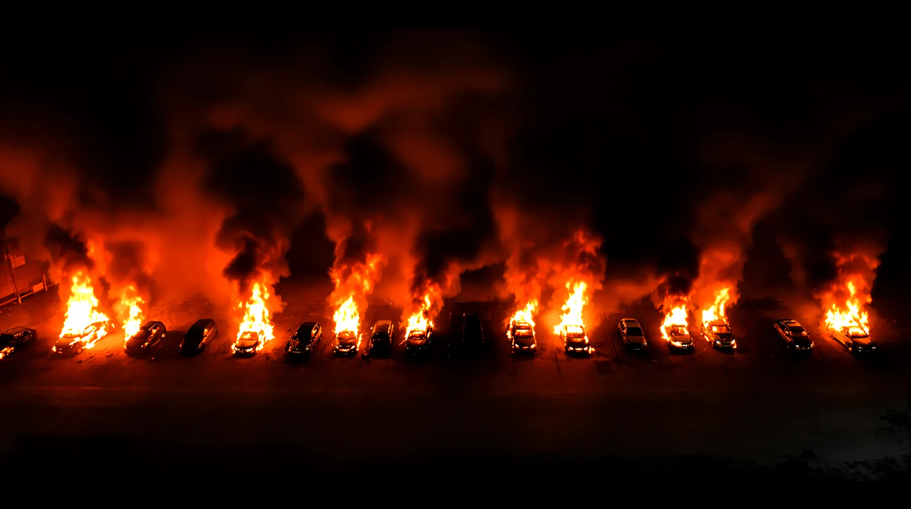 Illustration: a line of anonymous cars alight in a salvage yard at night, each with its own column of flame and smoke.